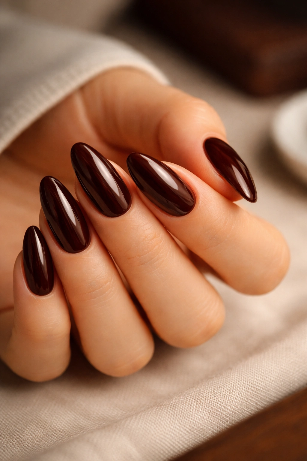 Close-up of almond nails in Espresso Brown with warm red undertone