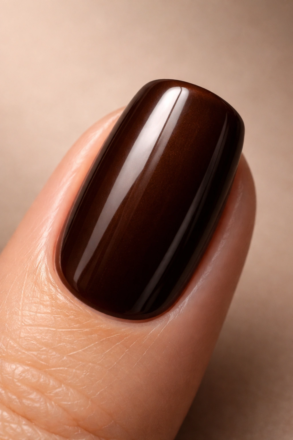 Close-up of a fingernail in espresso brown polish with warm undertones
