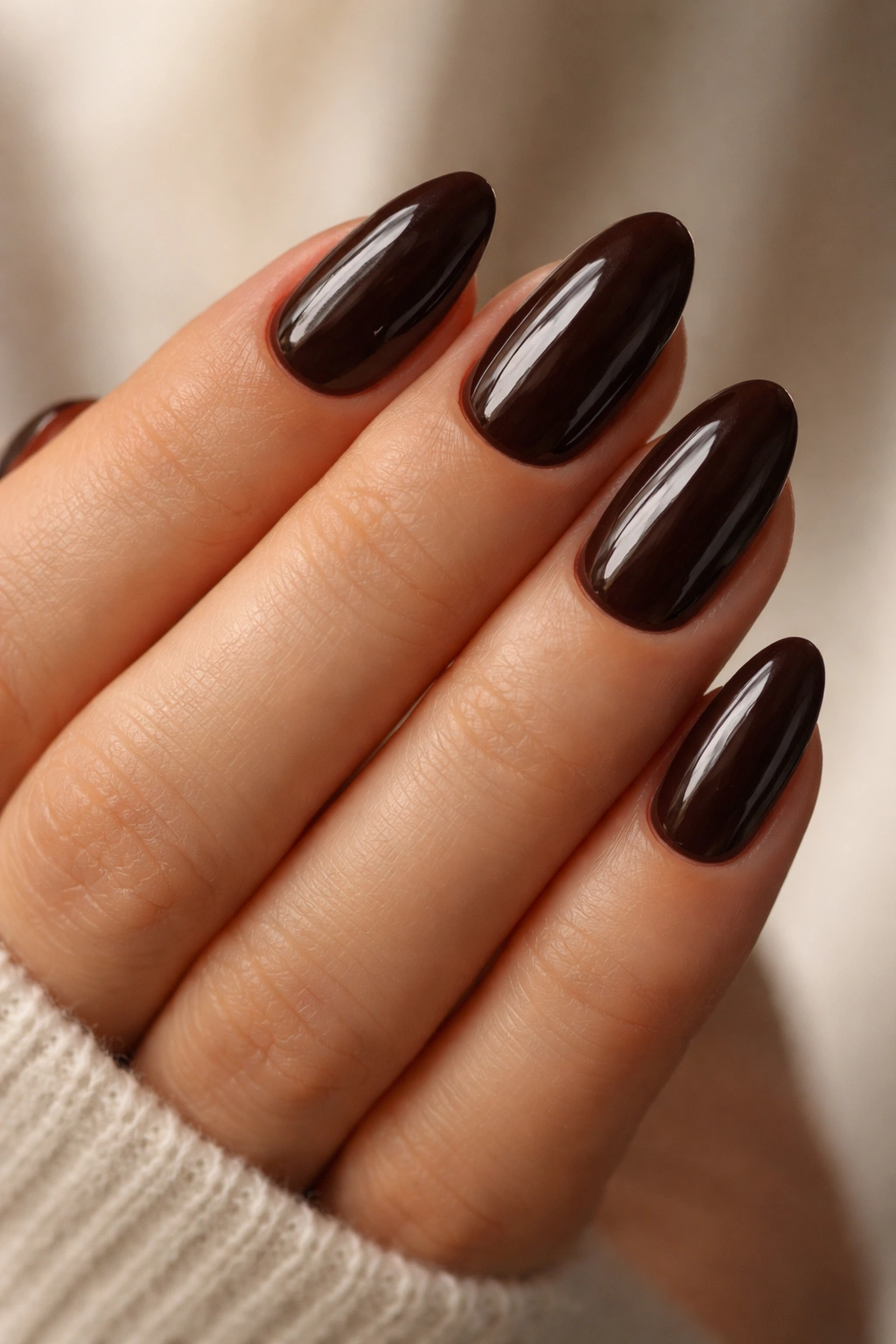 Close-up of short almond nails in espresso glossy brown.