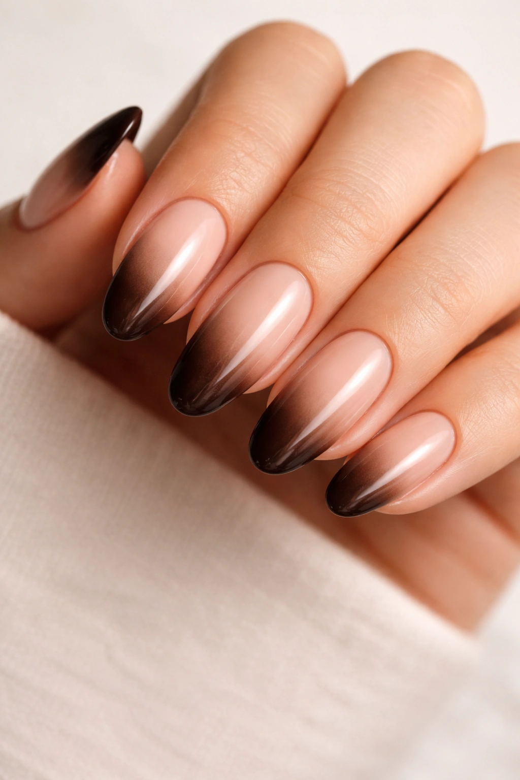 Close-up of a long oval nail with espresso gradient at the tips