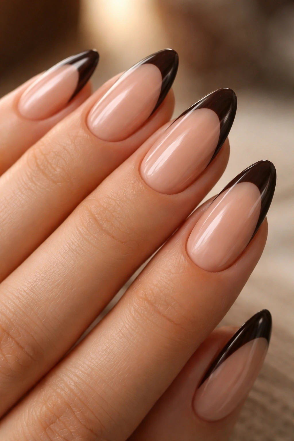 Almond nails with espresso tips along a thin smile line in warm light.
