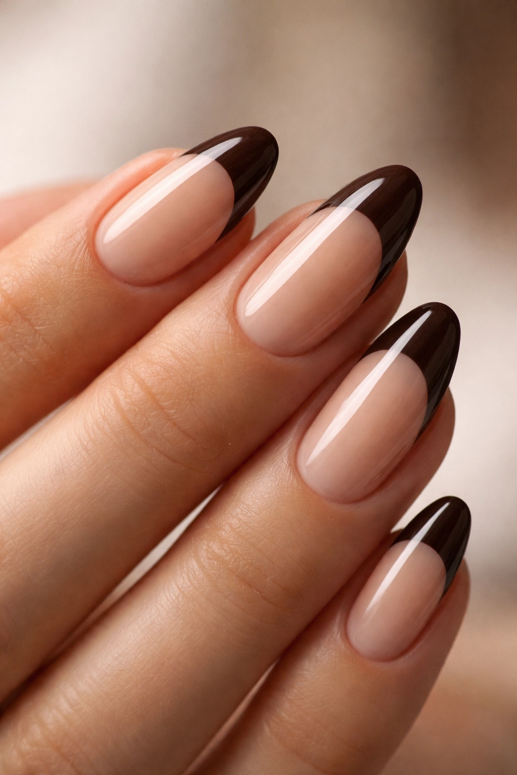 Close-up of a short almond nail with espresso brown tip on nude base