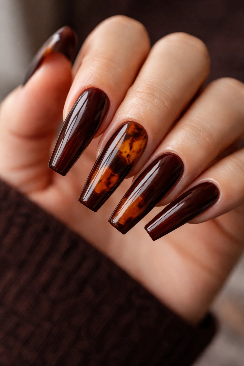 Close-up of espresso brown ballerina nails with tortoiseshell accents on long coffin nails