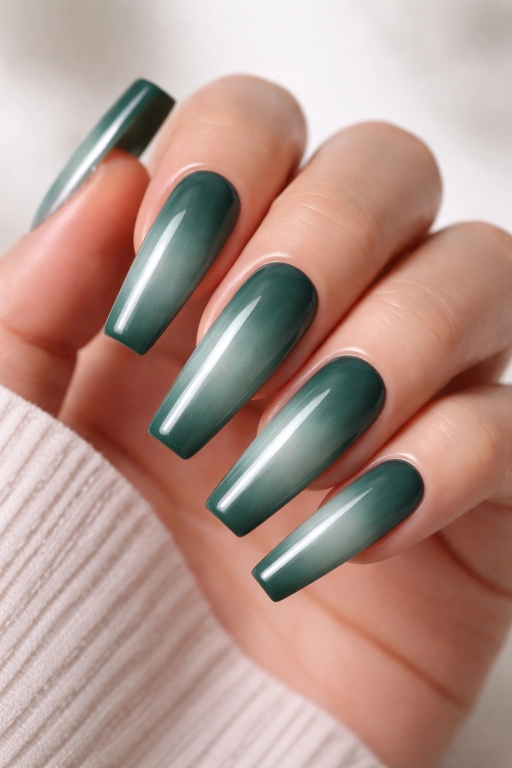 Close-up of long coffin nails in evergreen with a white milk bath finish