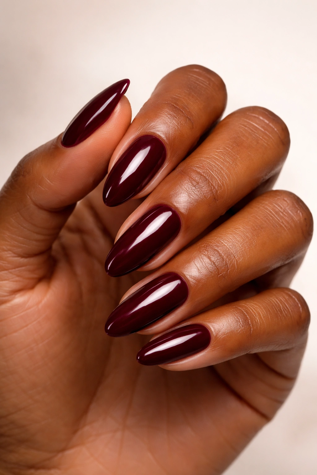 Close-up of a hand with burgundy nails reflecting final thoughts