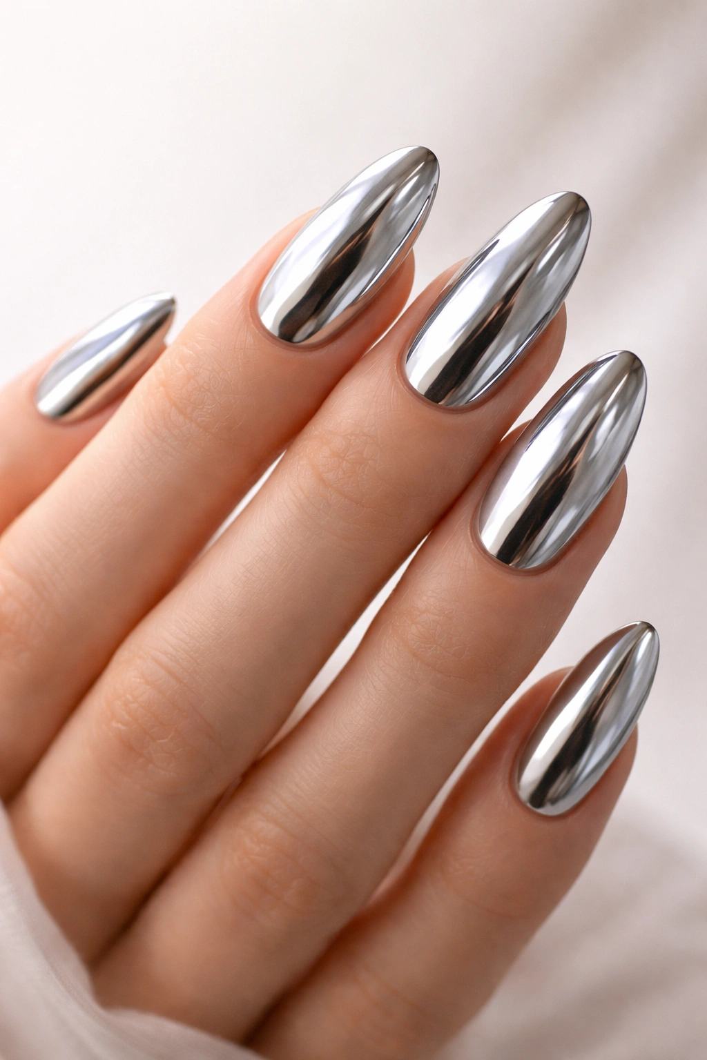 Close-up of a hand with long oval chrome nails showcasing a mirror finish