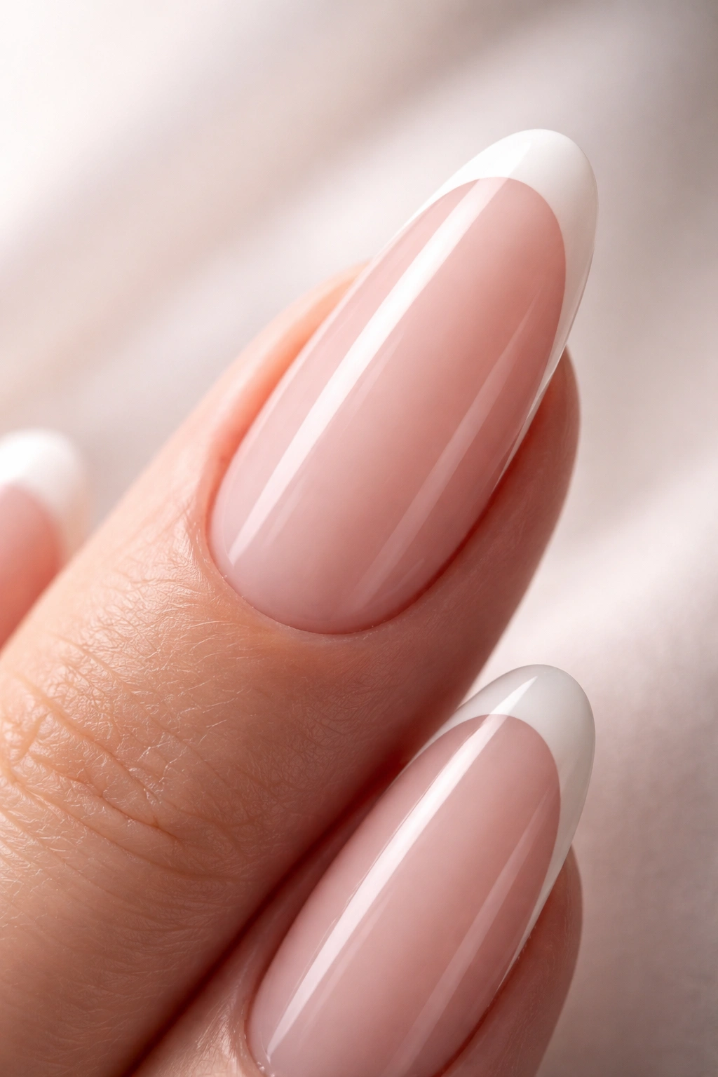 Close-up of a single long oval nail with a minimalist thin-line French tip on a neutral base