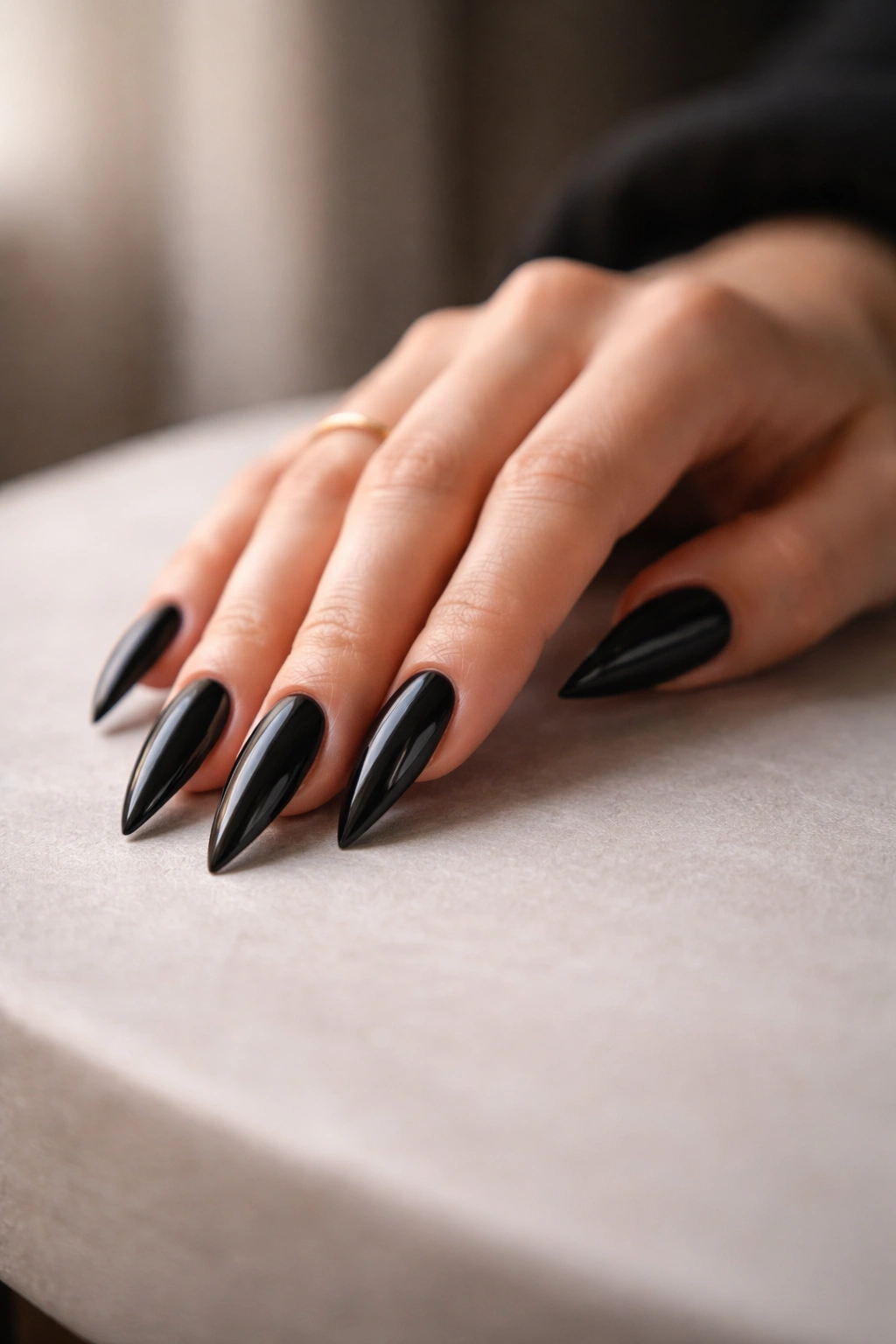 Hand with black stiletto nails resting on a surface