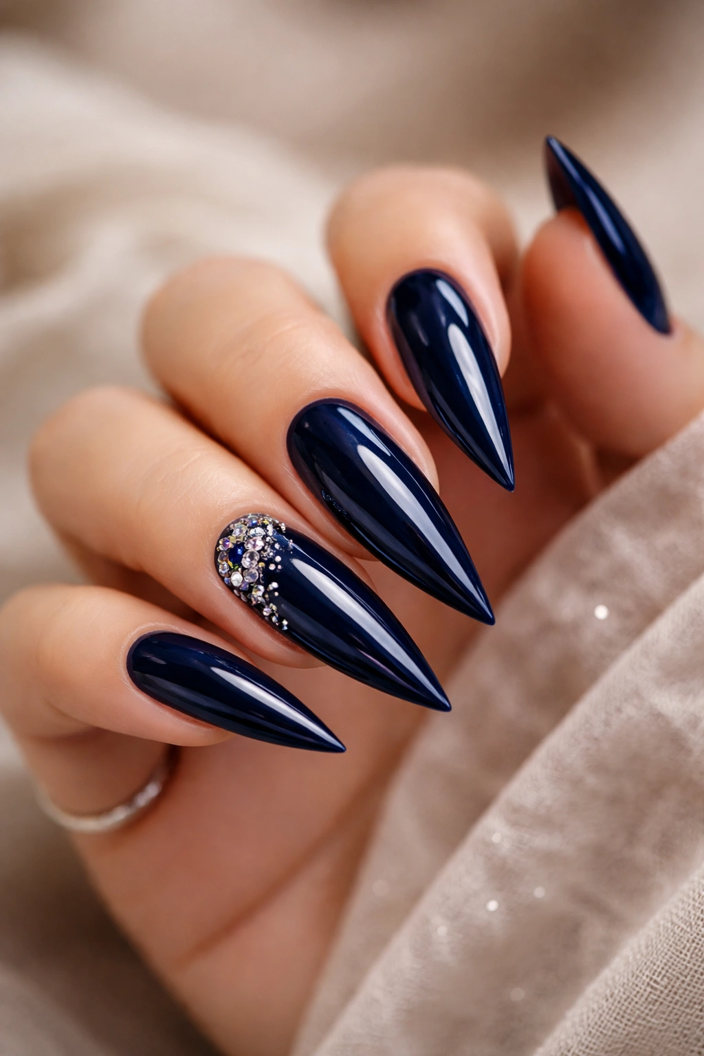 Close-up of dark blue stiletto nails with a glossy finish.