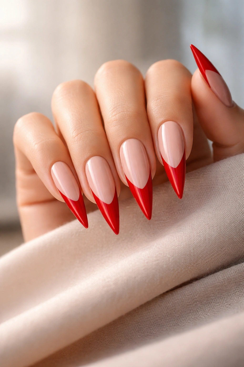 Close-up of a hand with red French tip stiletto nails, glossy manicure
