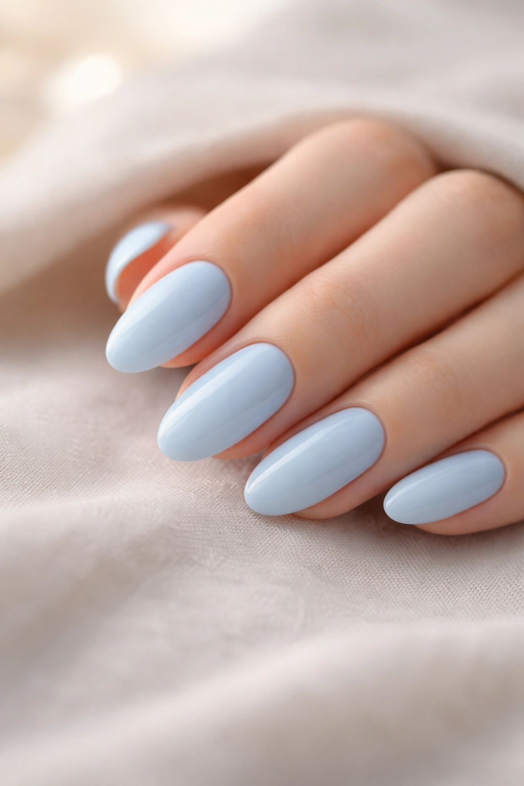 Minimalist close-up of light blue nails with soft lighting on neutral surface
