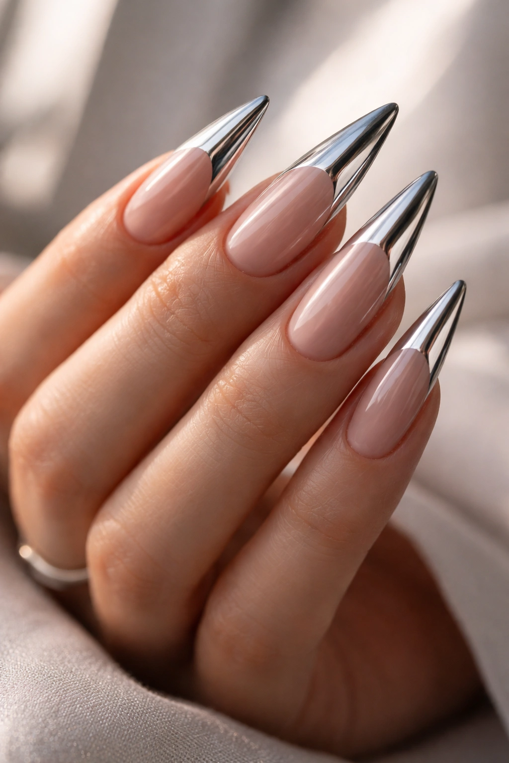 Close-up of chrome stiletto nails in a studio setting
