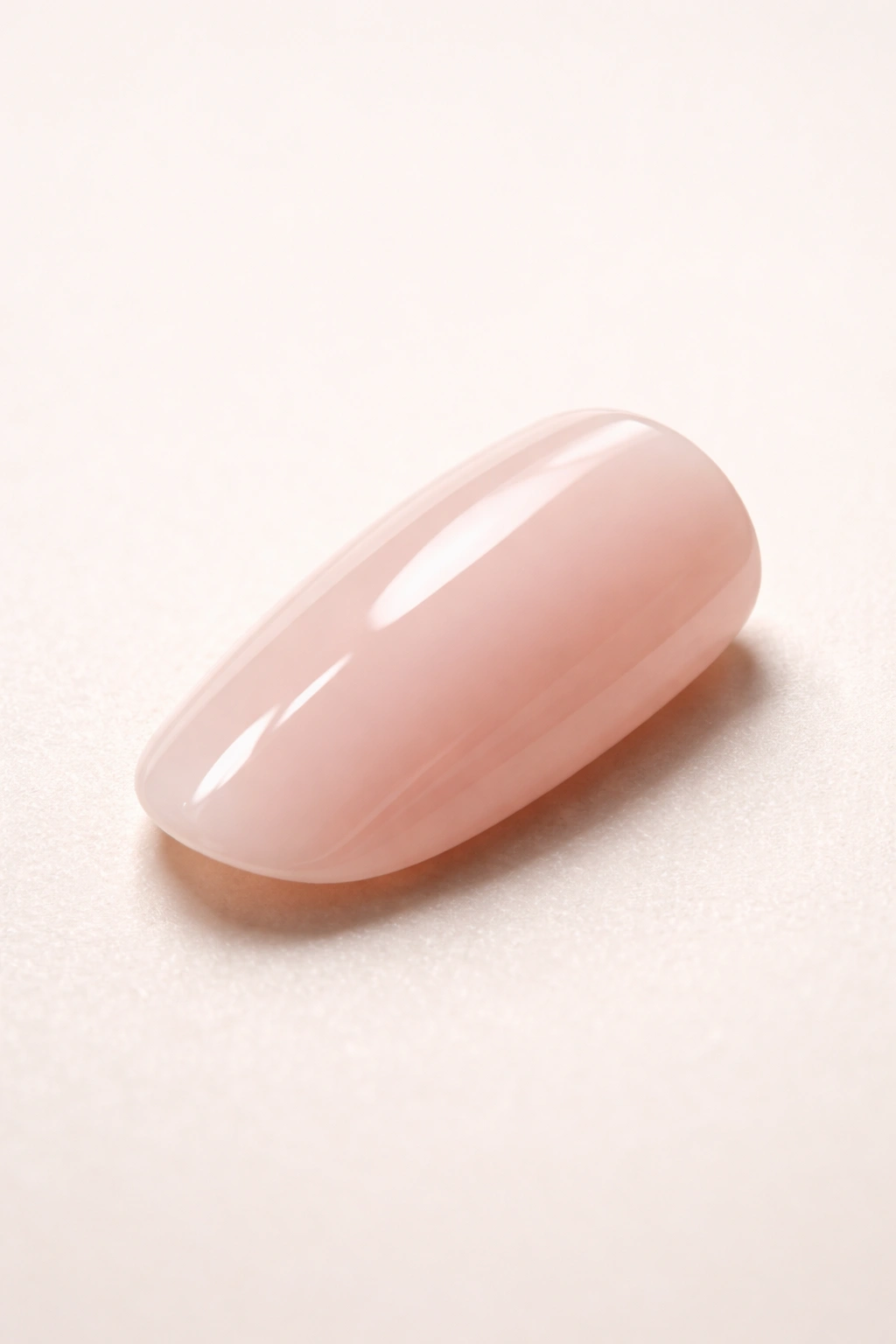 Close-up of a single glossy press-on nail on a neutral surface