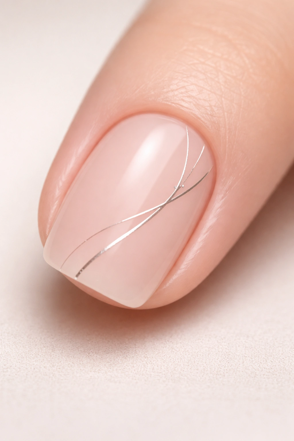 Close-up of a single short squoval nail with subtle line art
