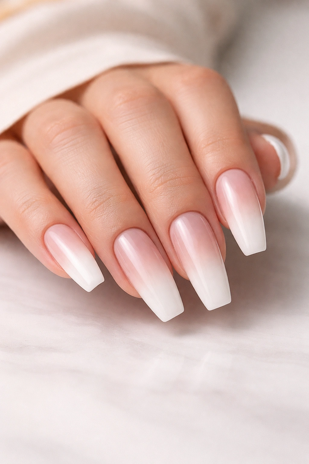 Close-up of coffin nails in a soft ombre palette on a clean surface