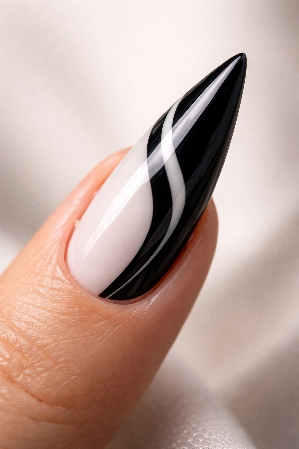Close-up of a black and white stiletto nail on a neutral background