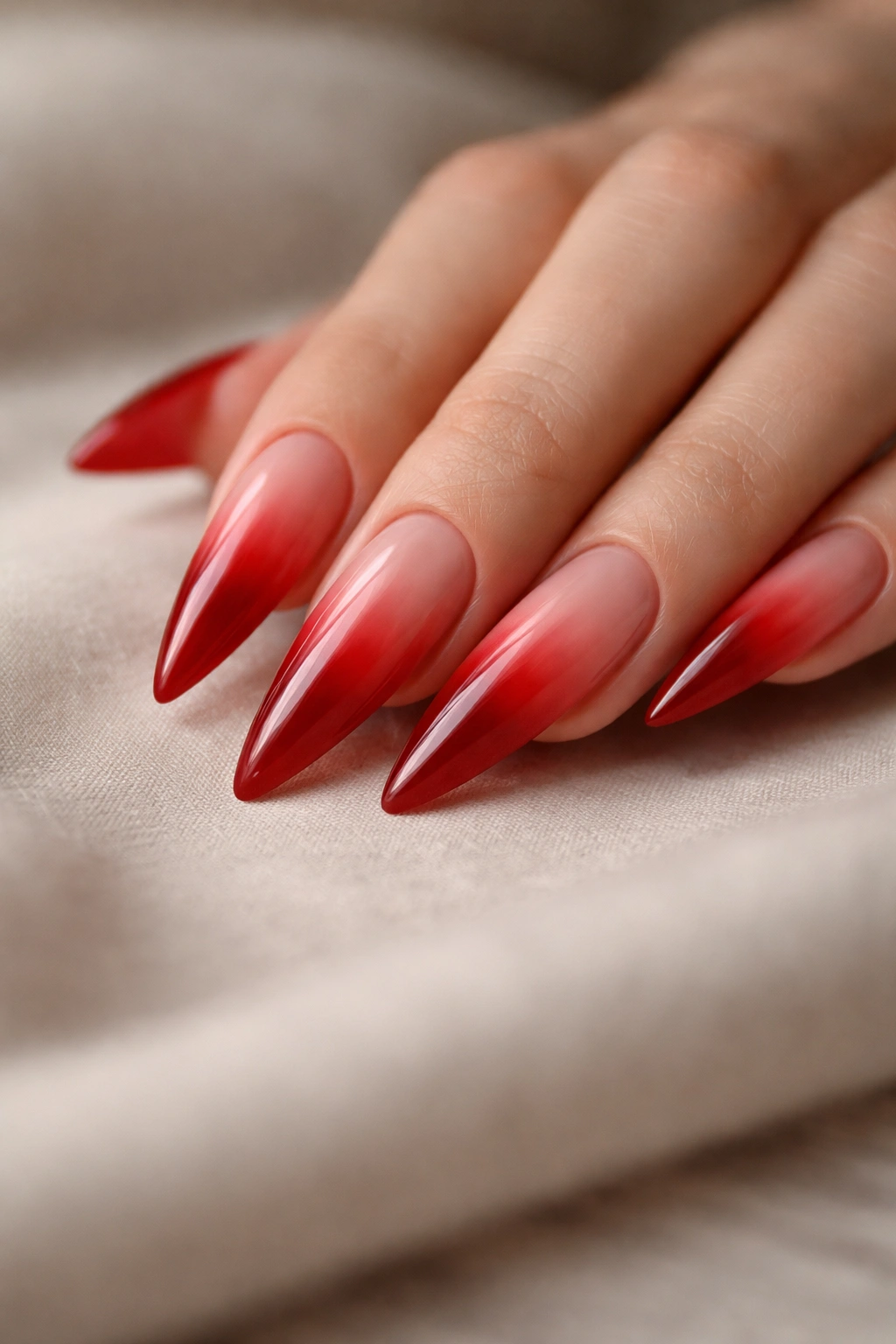 Close-up of red ombre stiletto nails resting on a hand