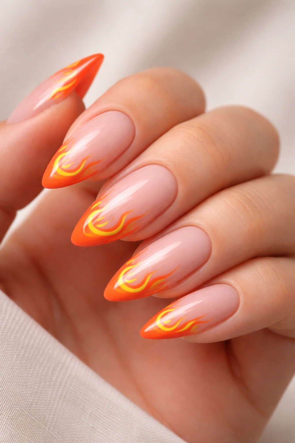 Close-up of almond nails with orange flame accents on French tips