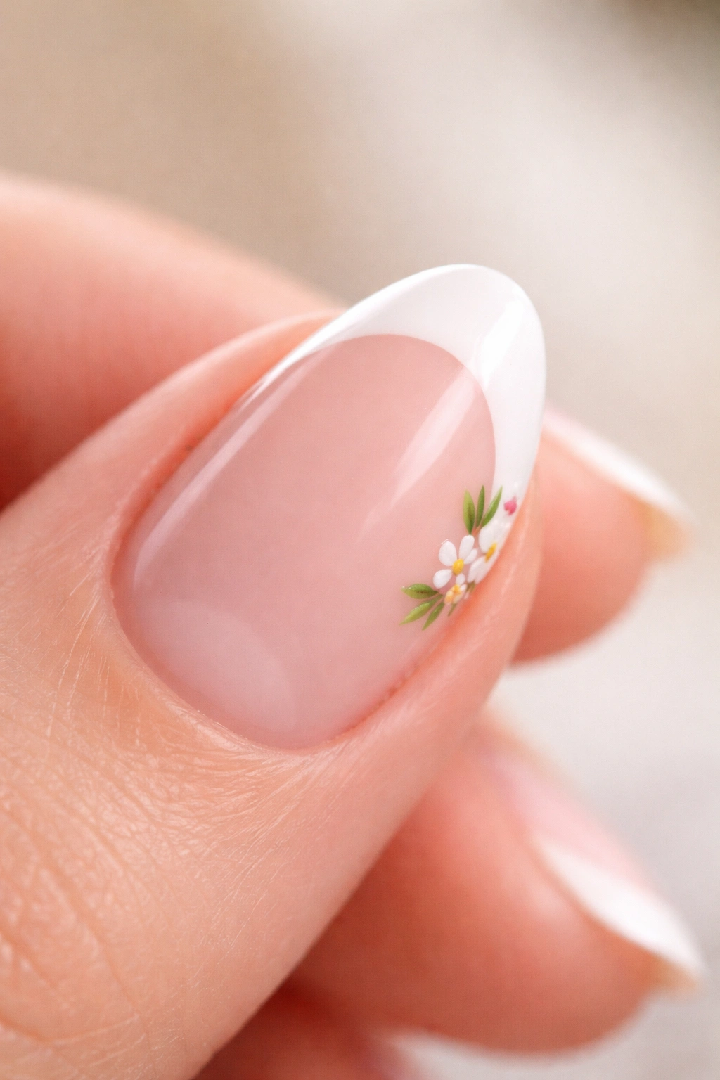 Close-up of a short almond nail with a small flower accent at the corner of the white tip