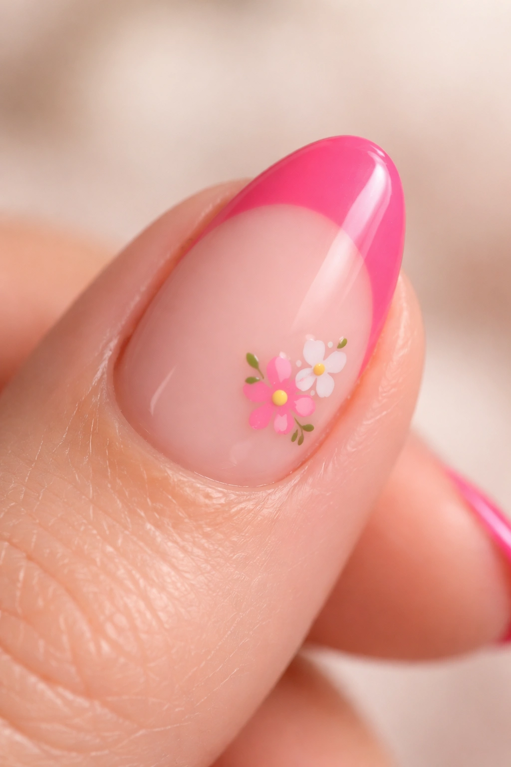 Close-up of a short almond nail with hot pink tip and a small floral accent near the cuticle