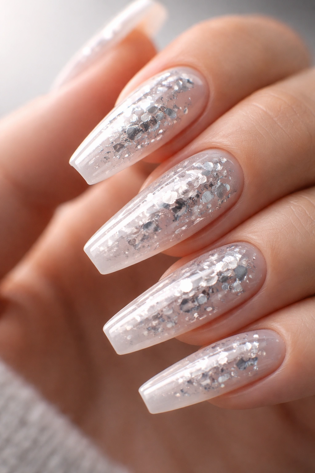 Close up of a ballerina nail with crushed silver foil suspended in milky gel