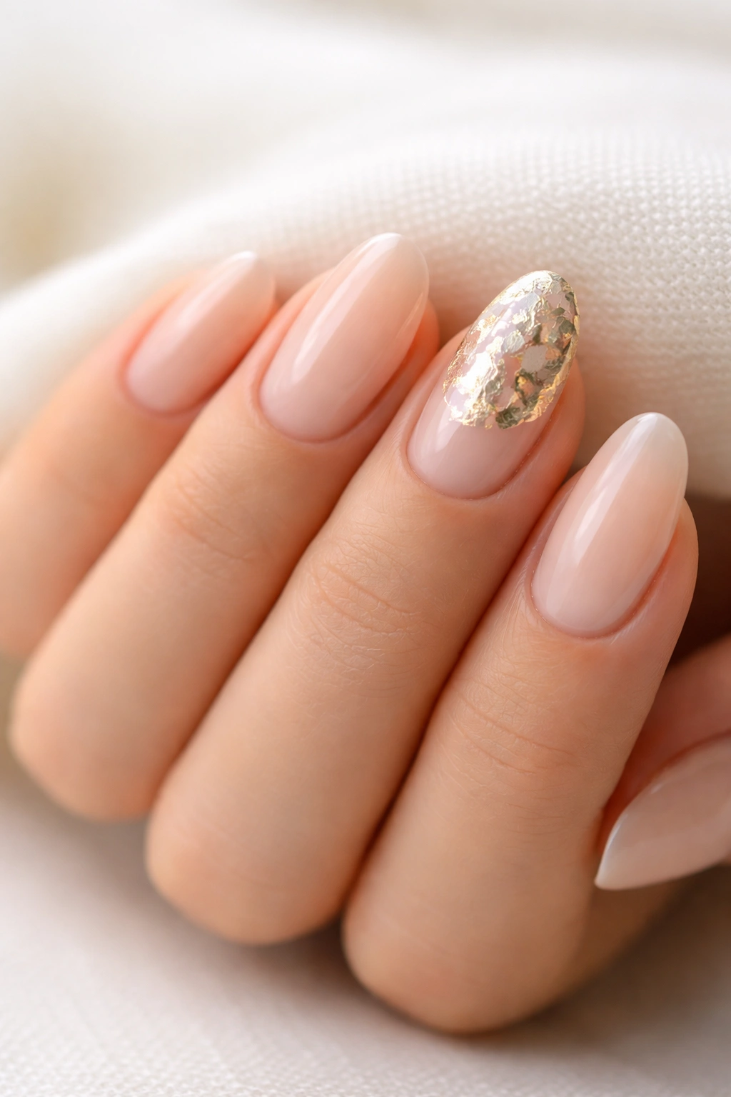 Nude nails with subtle foil patch on ring finger on short almond nails