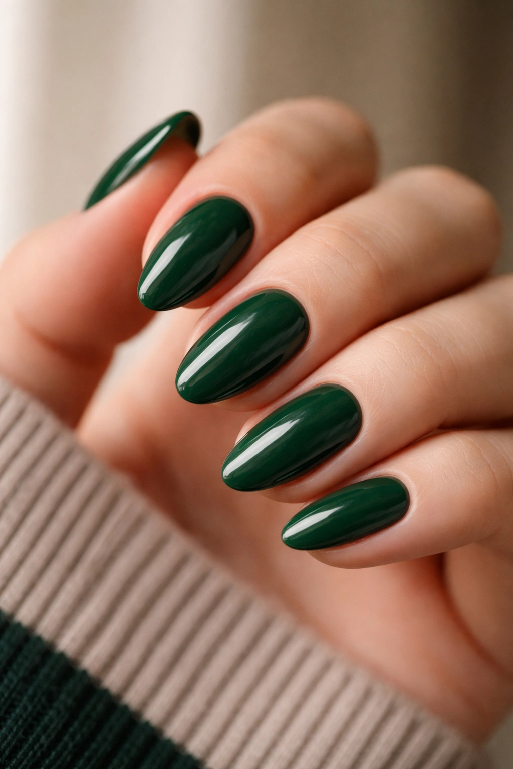 Close-up of short almond nails in forest green glossy polish