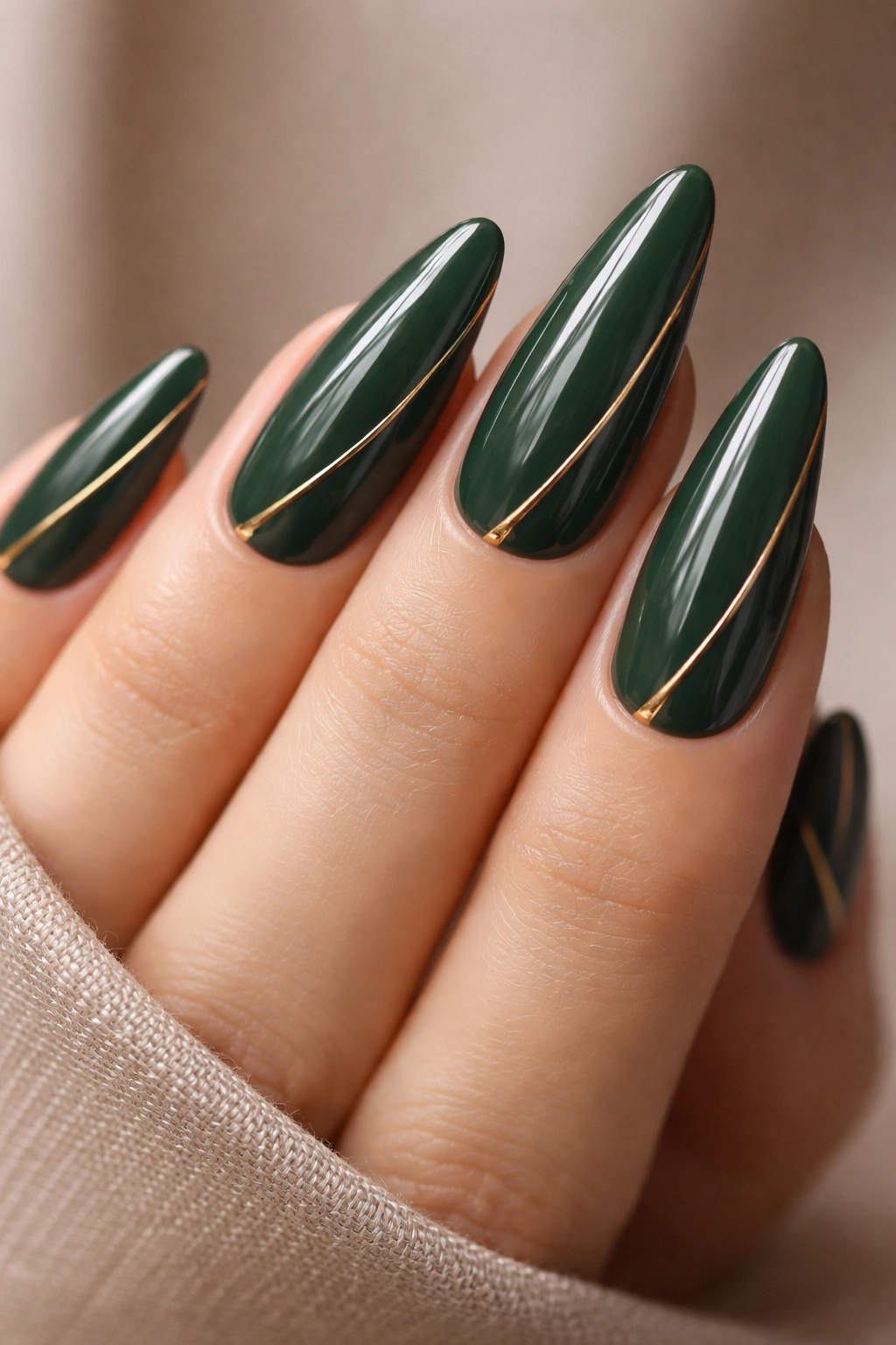 Close-up of forest green nails with gold line accents on a neutral background