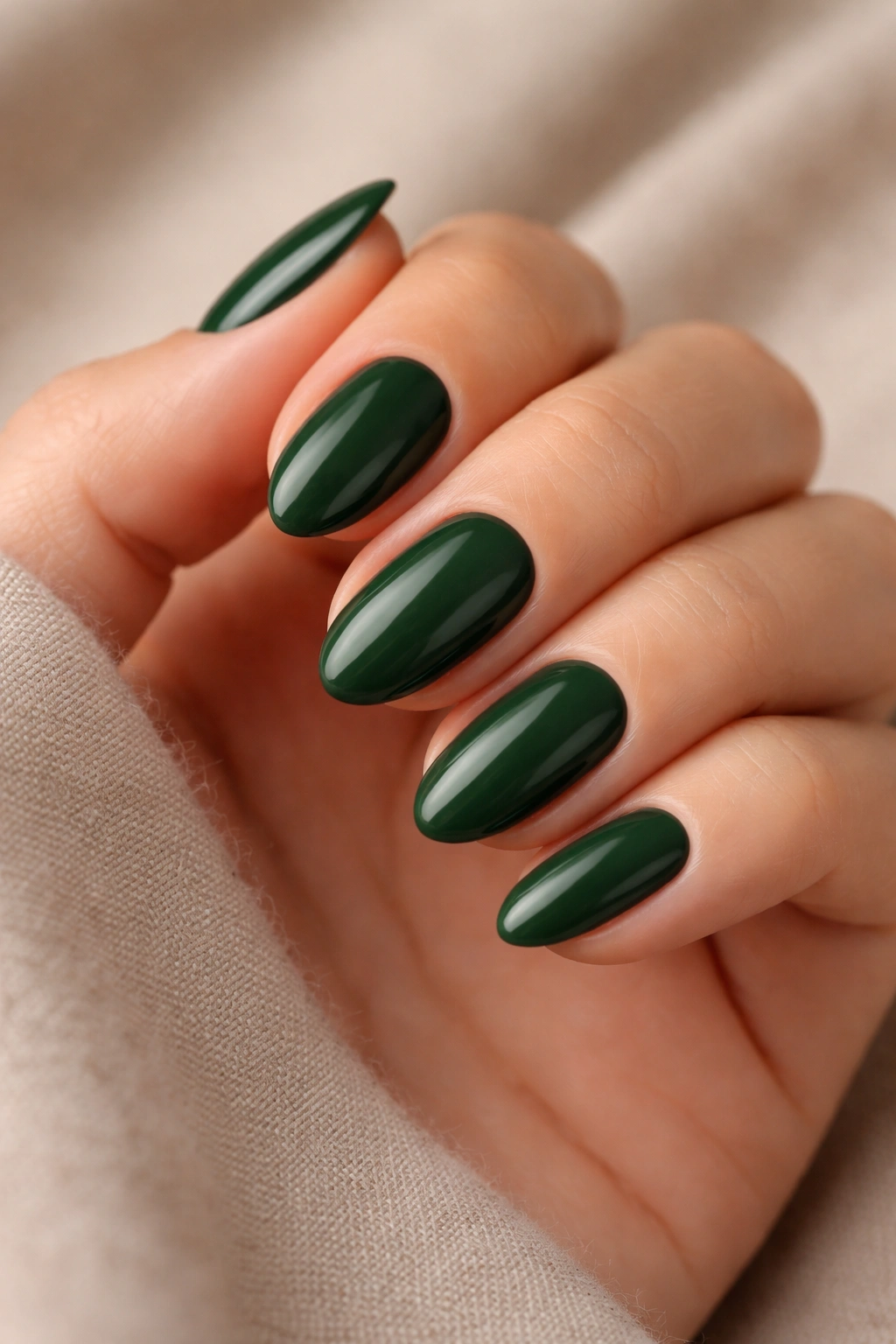 Close-up of deep forest green almond nails on a bare hand