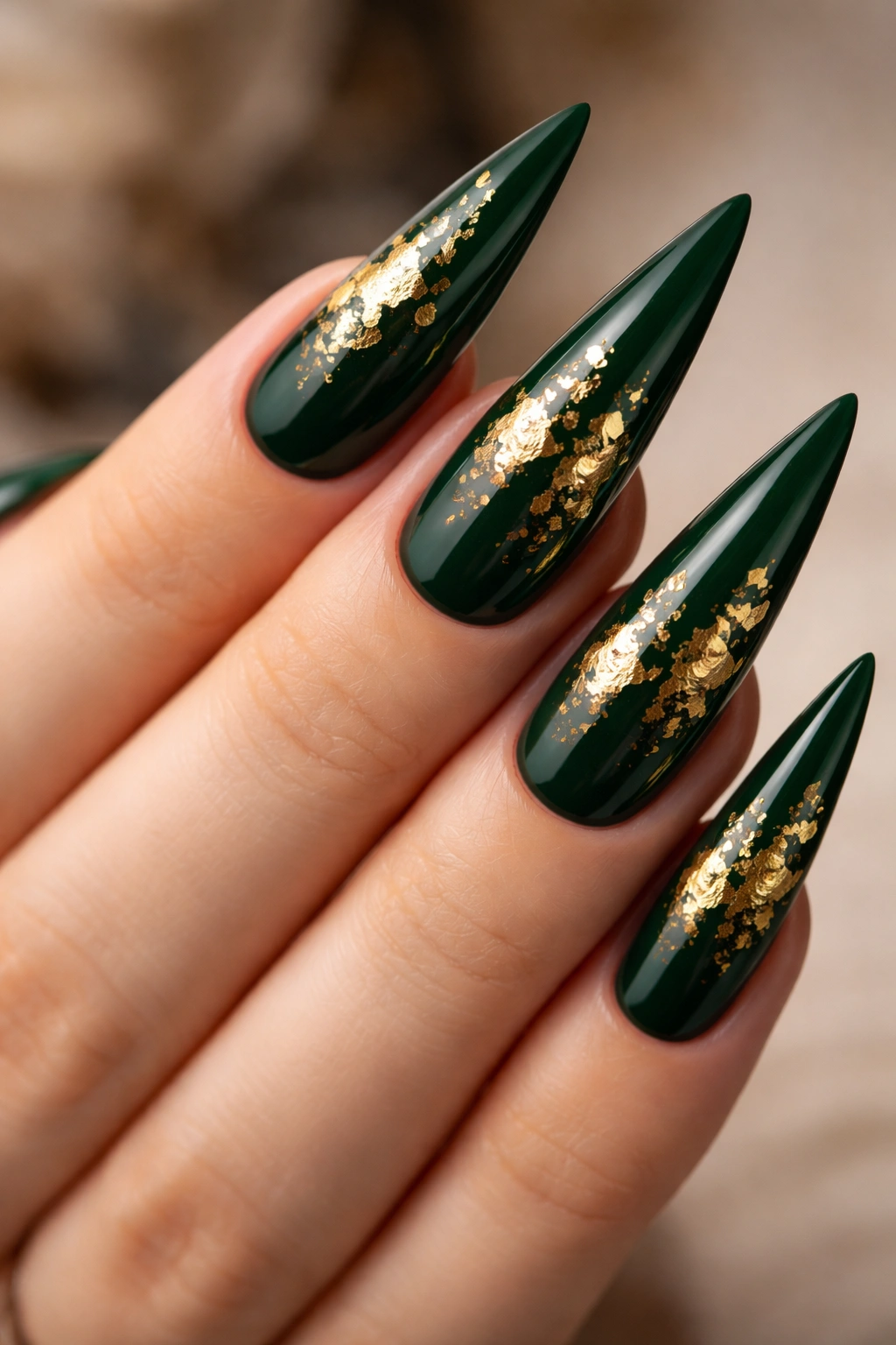 Close-up of forest green stiletto nails with gold leaf details
