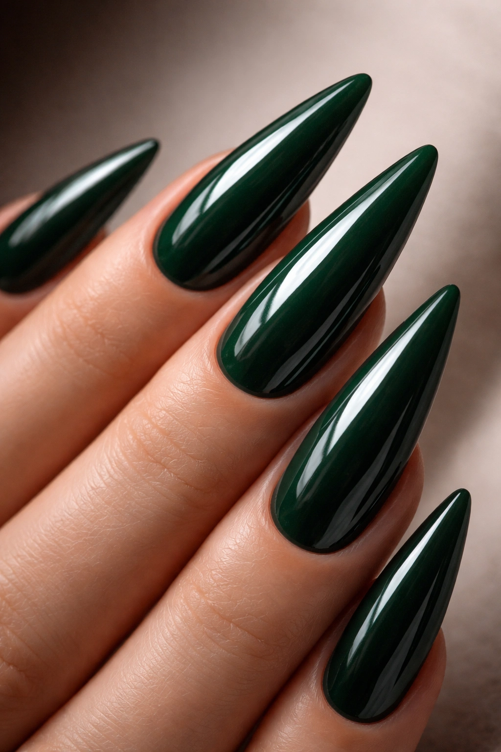 Close-up of high-gloss forest green stiletto nails on a neutral background