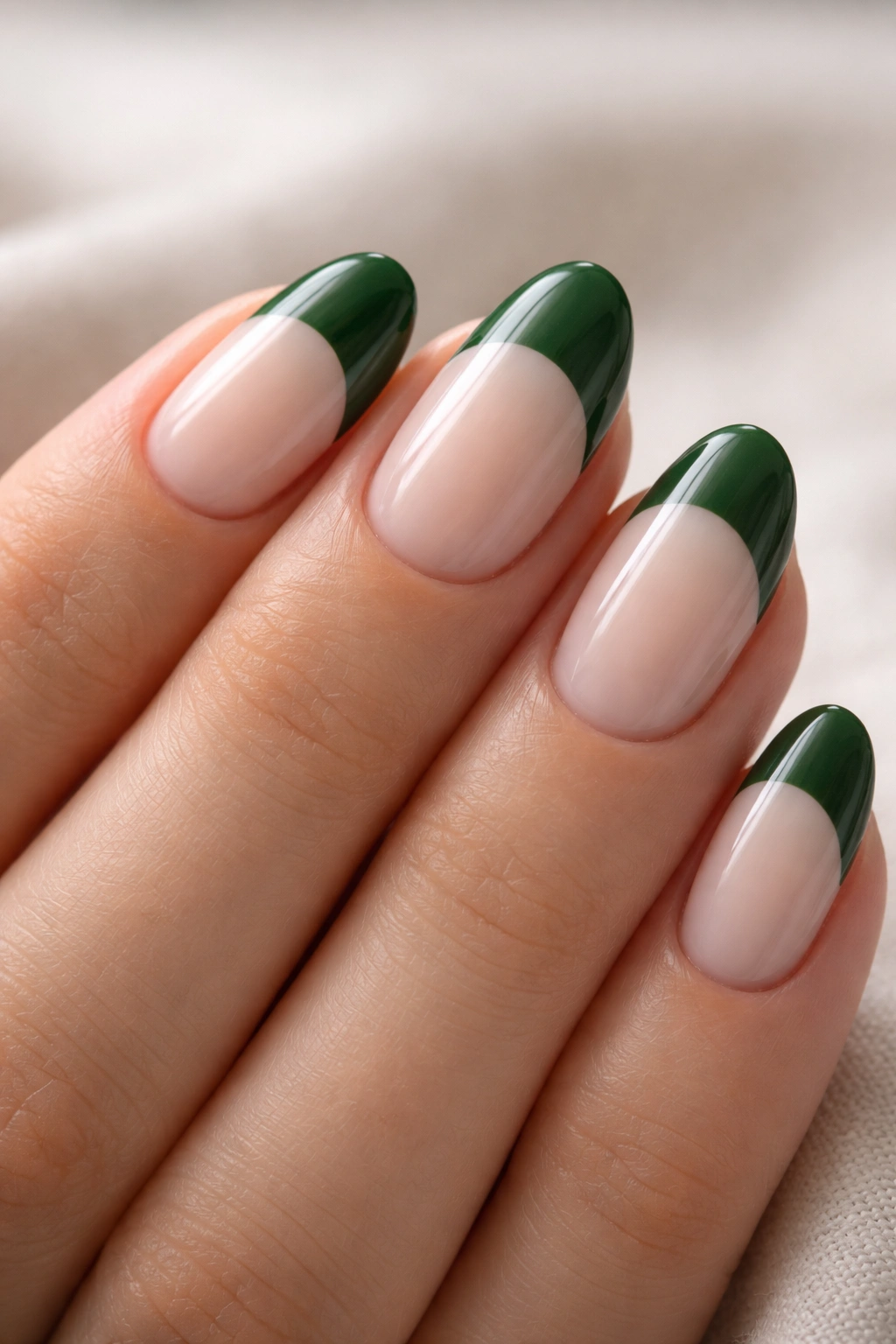 Close-up of short almond nails with a forest green thick band on milky white base