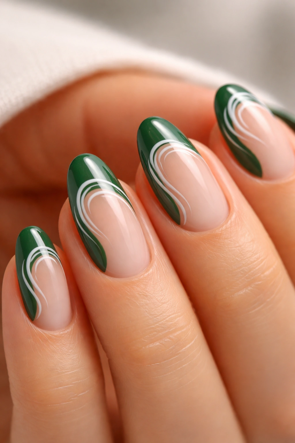 Close-up of a short almond nail with forest green tip and white swirl art