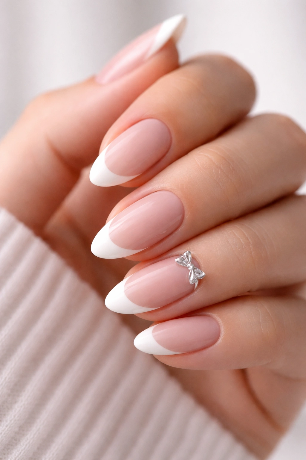 Short almond nails with French tips and a single bow accent