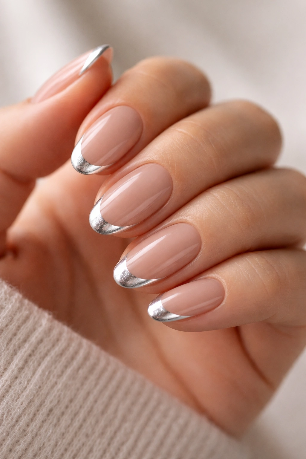 Close-up of French almond nails with silver smile lines on a nude base