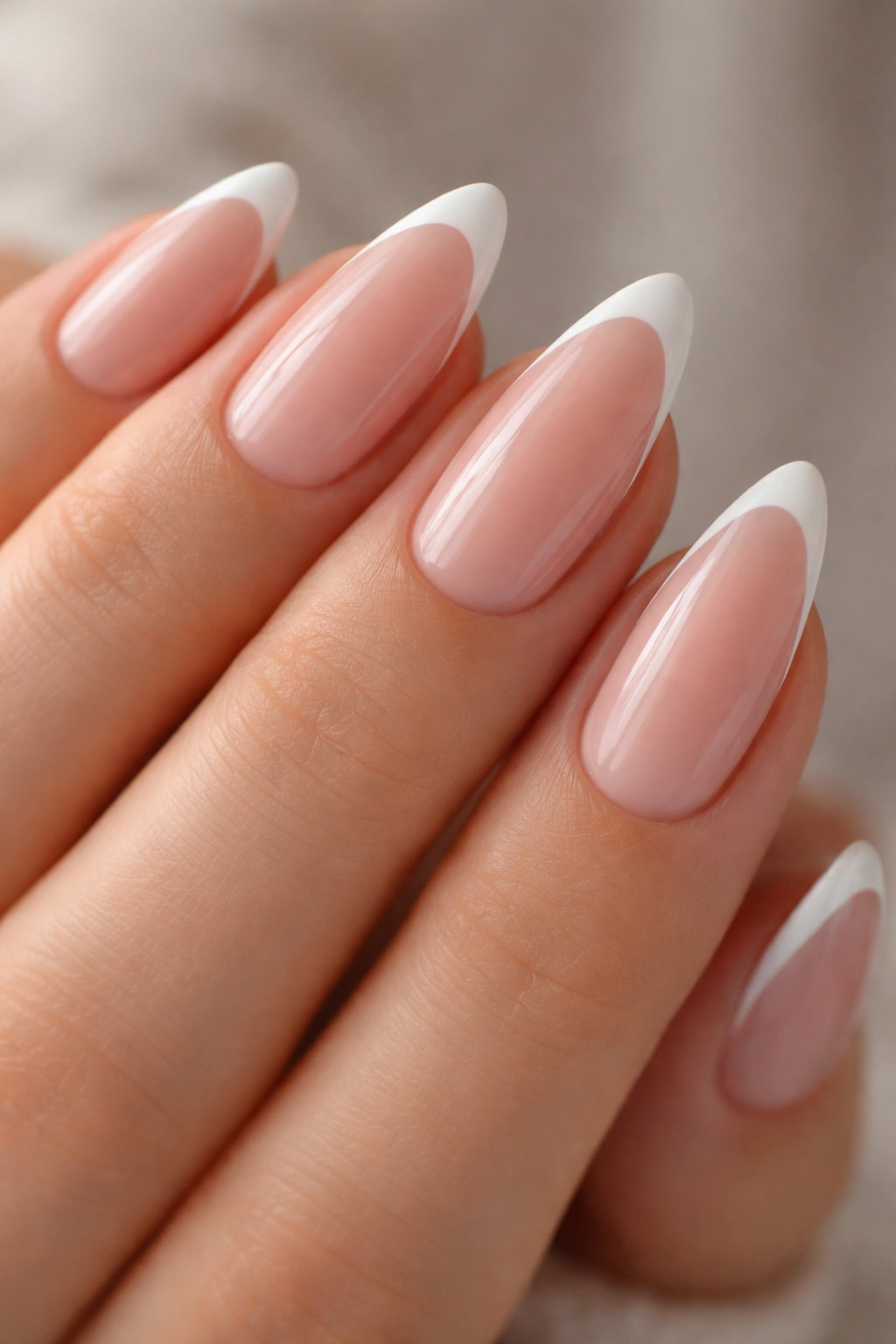 Close-up of almond nails with ultra-thin white tips on nude base