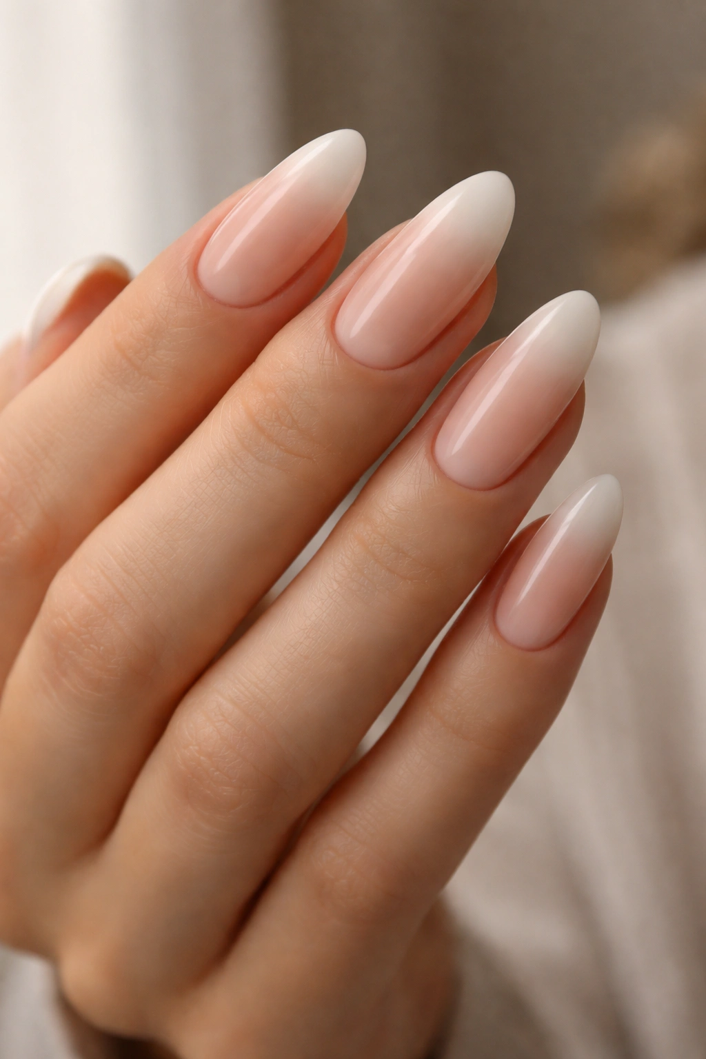 Close-up of long oval nails with a soft white-to-pink French fade