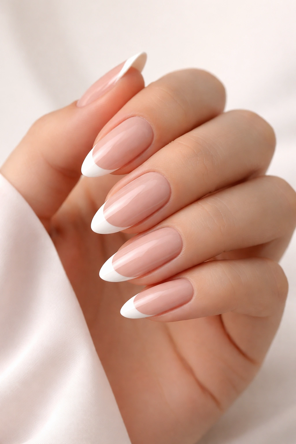 Close-up of classic French manicure on almond nails with pink nude base