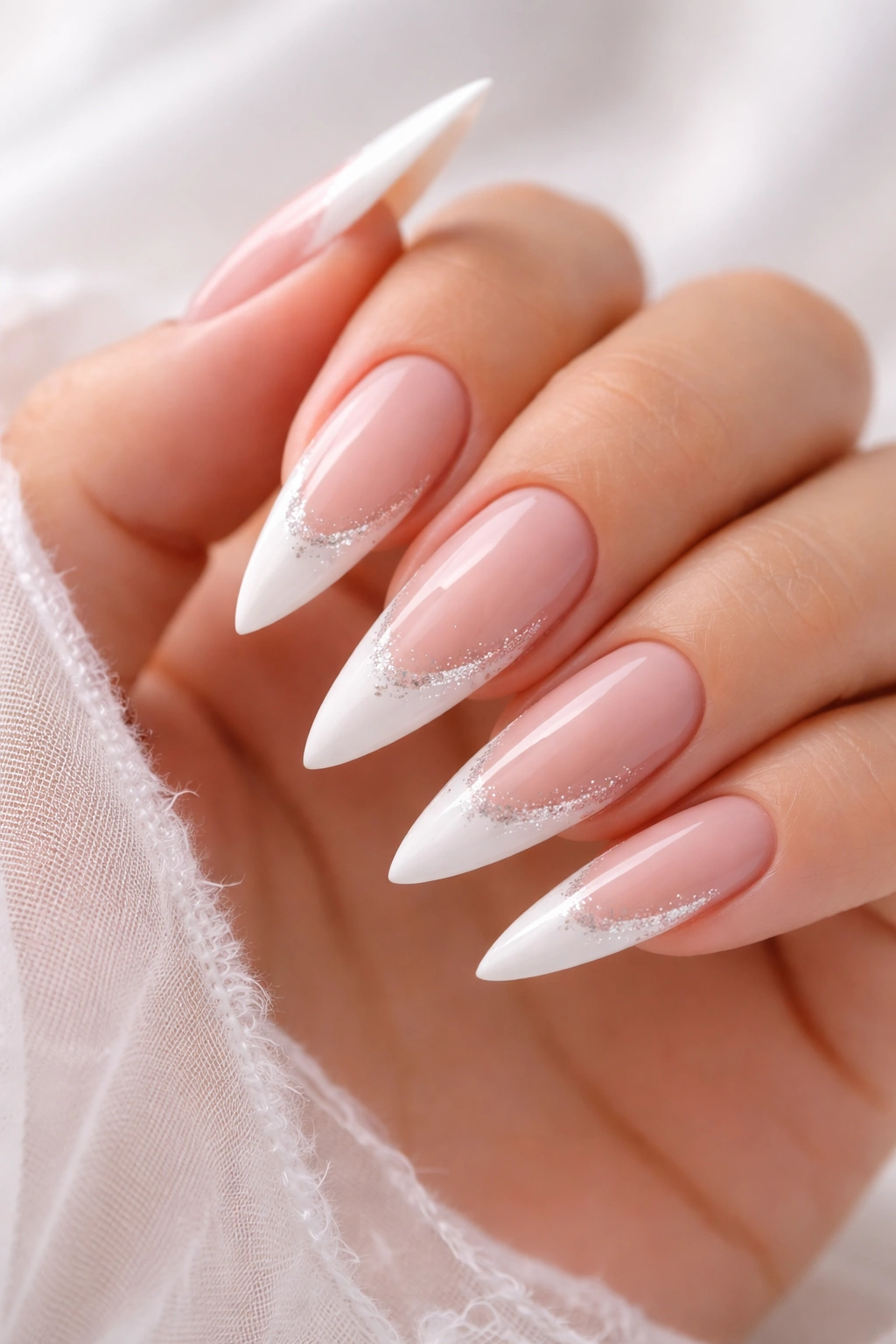 Close-up of nude-based stiletto nails with white tips and subtle glitter