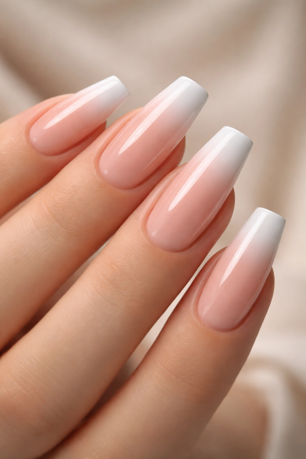Close-up of coffin nails with French-inspired nude ombre, sheer pink base fading to white tips