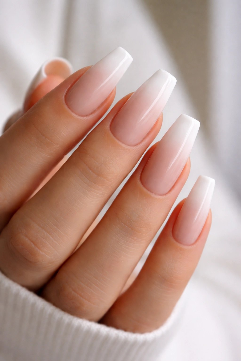 Close-up of wide coffin nails featuring a nude-to-white French ombre gradient on a clean hand