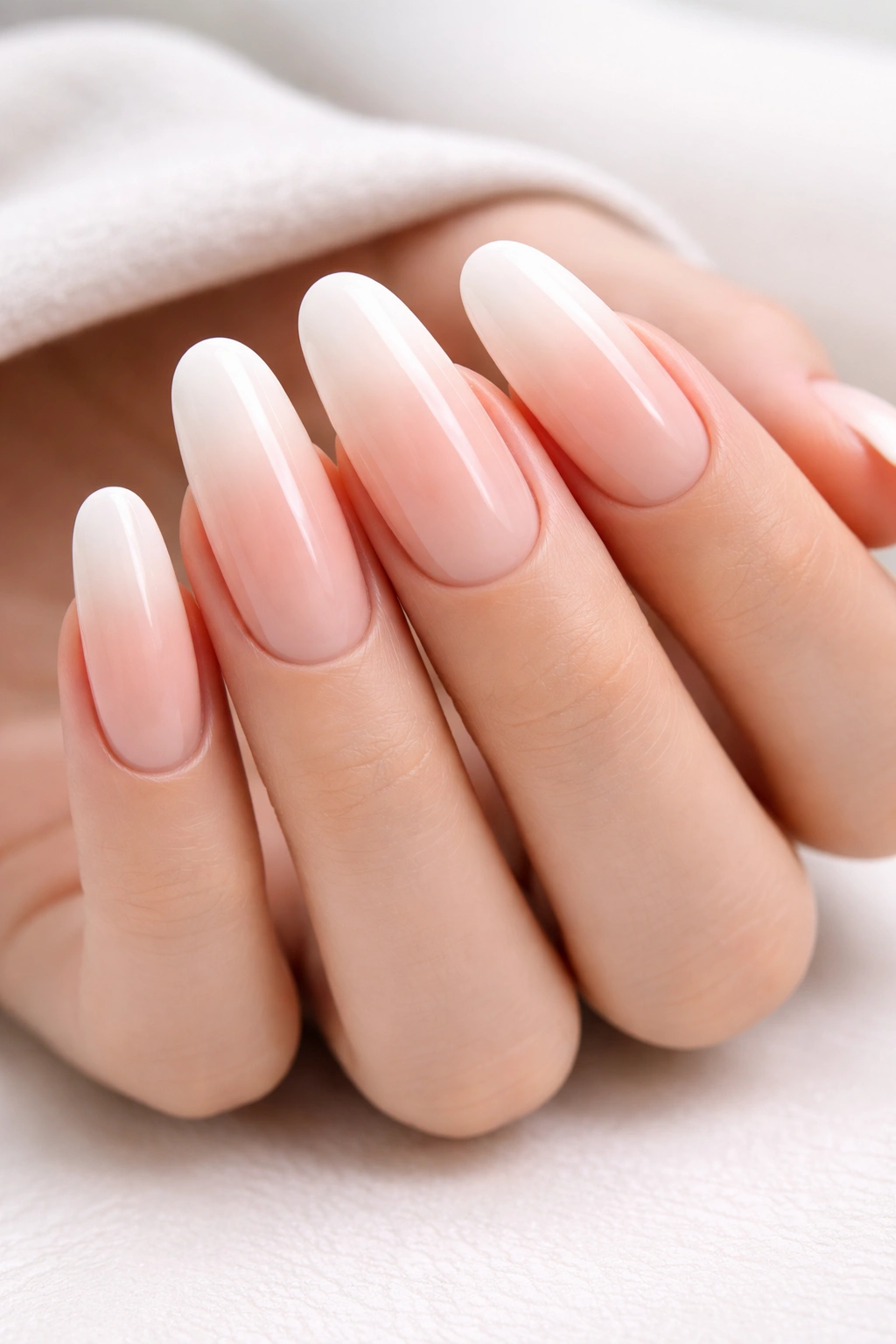 Close-up of long round acrylic nails with white-to-nude ombré French gradient