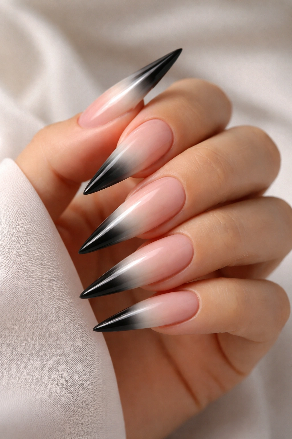 Close-up of stiletto nails with nude base and white-to-black ombre at the tips