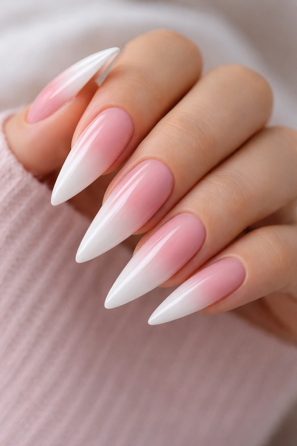 Close-up of stiletto nails with a white base and pink-to-white gradient tips.