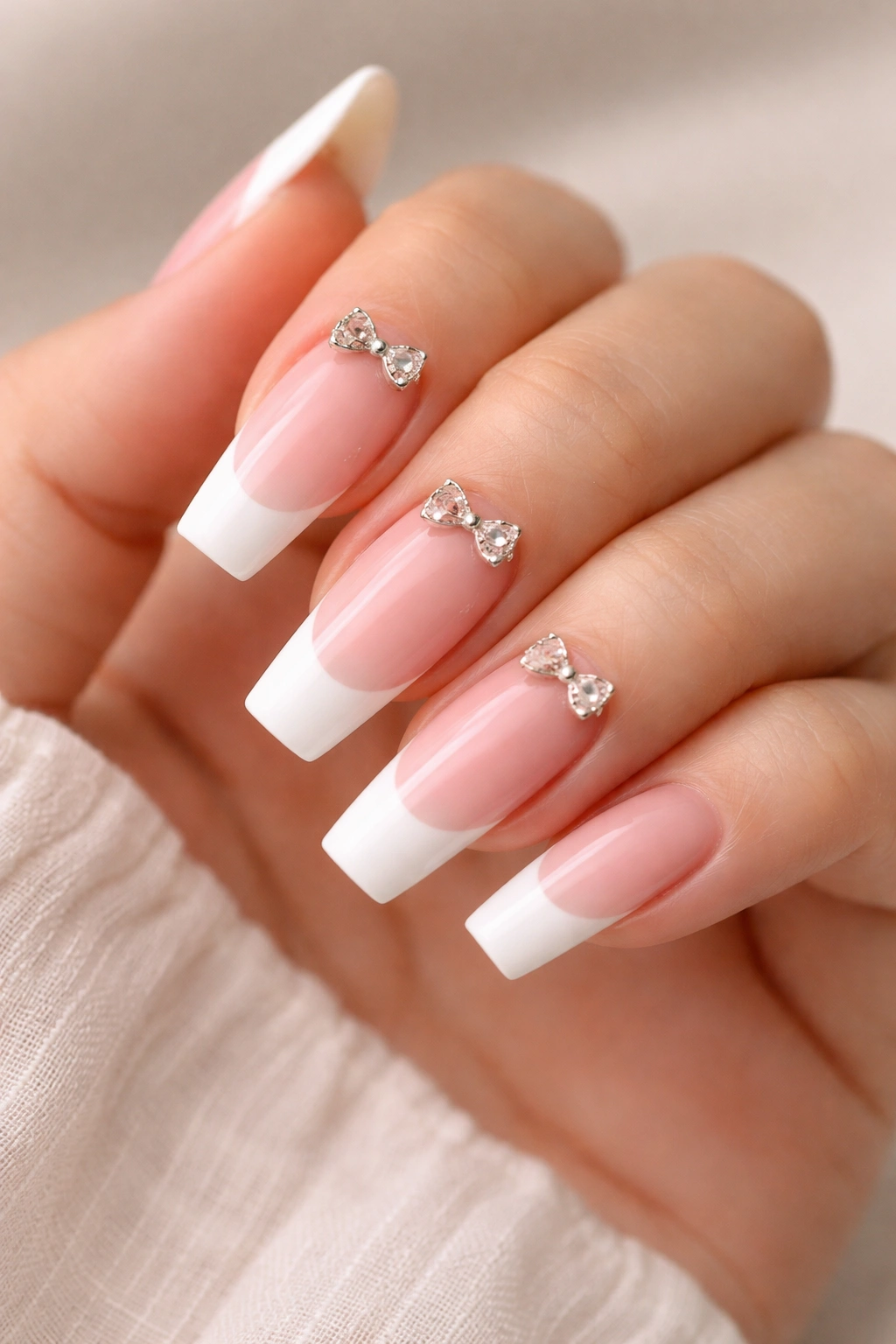 French tip ballerina nails with bow charms near the cuticle