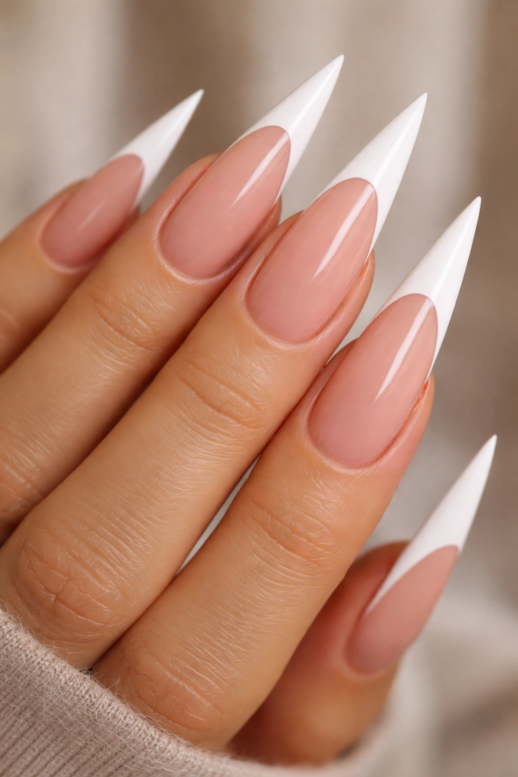Close-up of stiletto nails with bold thick white French tips on nude base