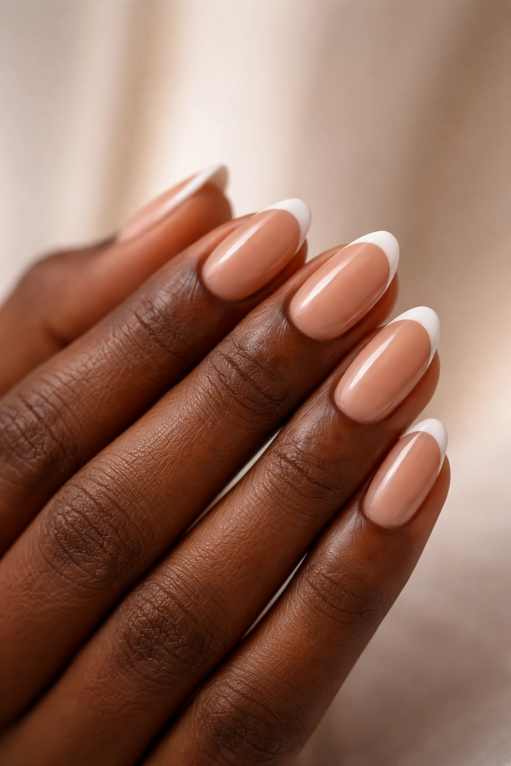 Close-up of French tips on short almond nails with a nude base