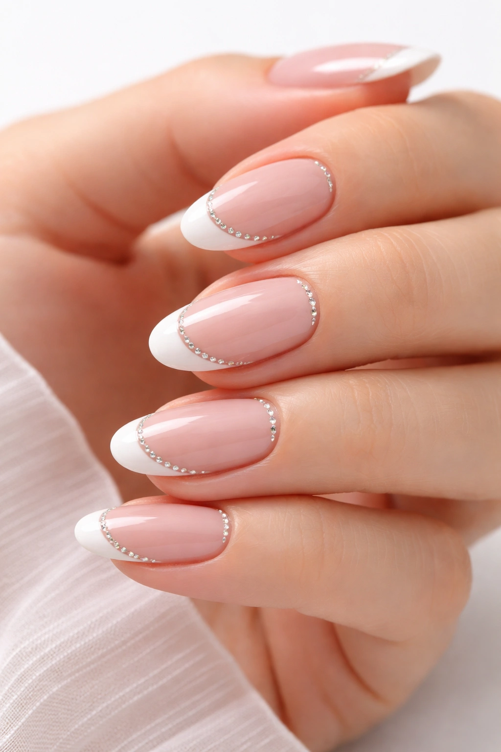 Close-up of short almond nails with French tips and tiny rhinestones along the smile line