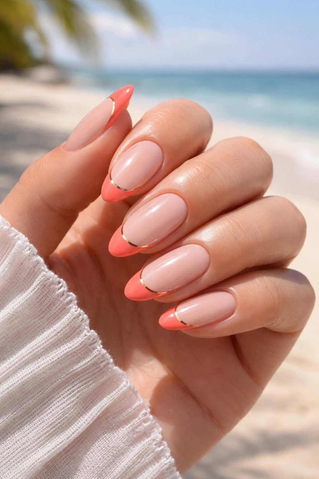 Close-up of hands with coral-tipped French manicure on nude base