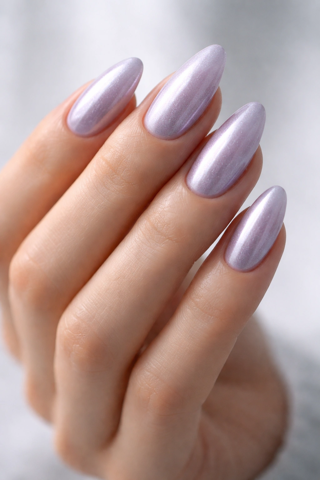 Close-up of frosted lilac almond nails on a pale hand